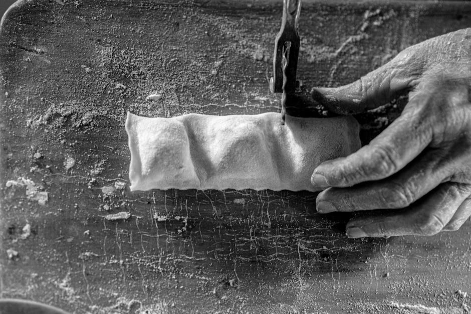 Hands cutting dough for panzerotti on a well-floured wooden board