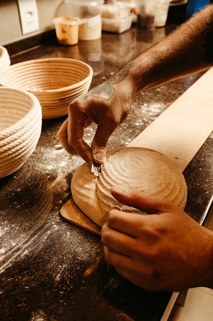 Baker's hands scoring round sourdough loaf in a Bari bakery