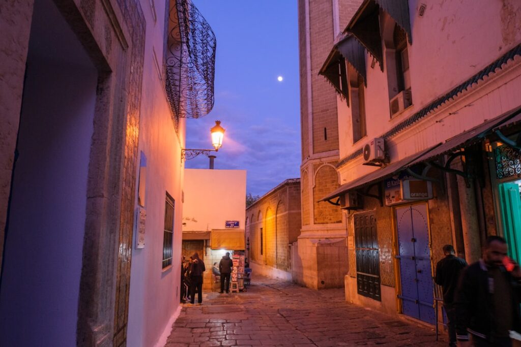 Ruelle pavée de Bari au crépuscule, lampadaire et passants