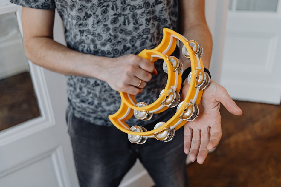 Hands holding bright yellow tambourines used in tarantella music