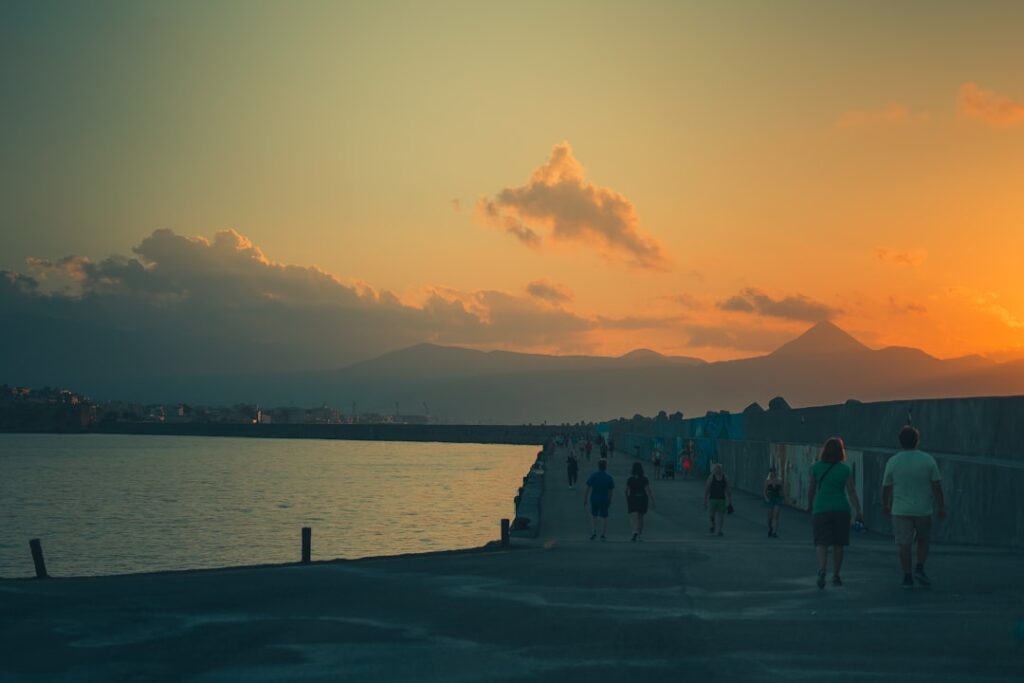 Promenade sur la digue de Bari au coucher de soleil, silhouettes de promeneurs