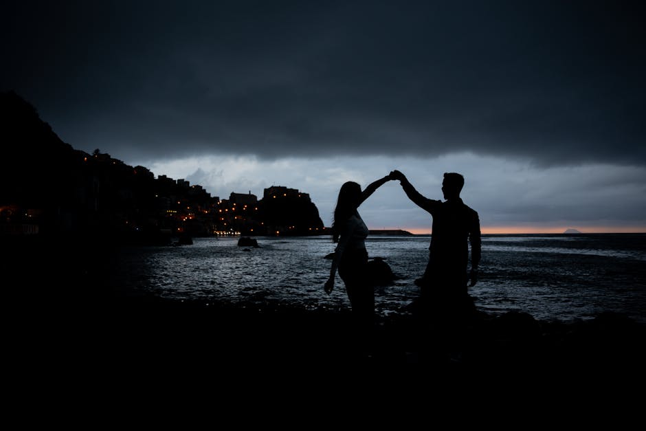 Silhouetted couple dancing on a beach at dusk by the sea