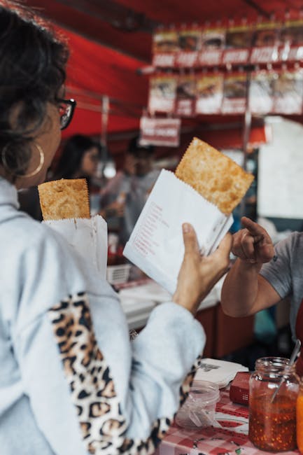 Street vendor handing over a hot panzerotto to a customer at a market in Bari