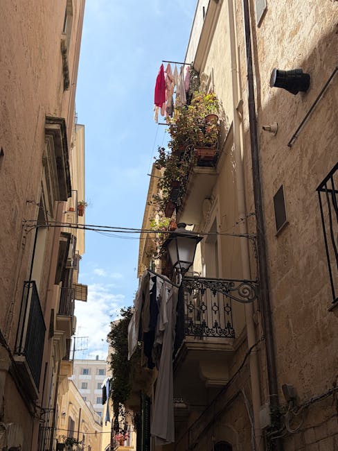 Stretto vicolo di Bari Vecchia con balconi fioriti e panni stesi.
