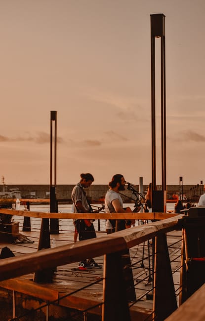 Musicians performing on a wooden pier at Bari waterfront during sunset