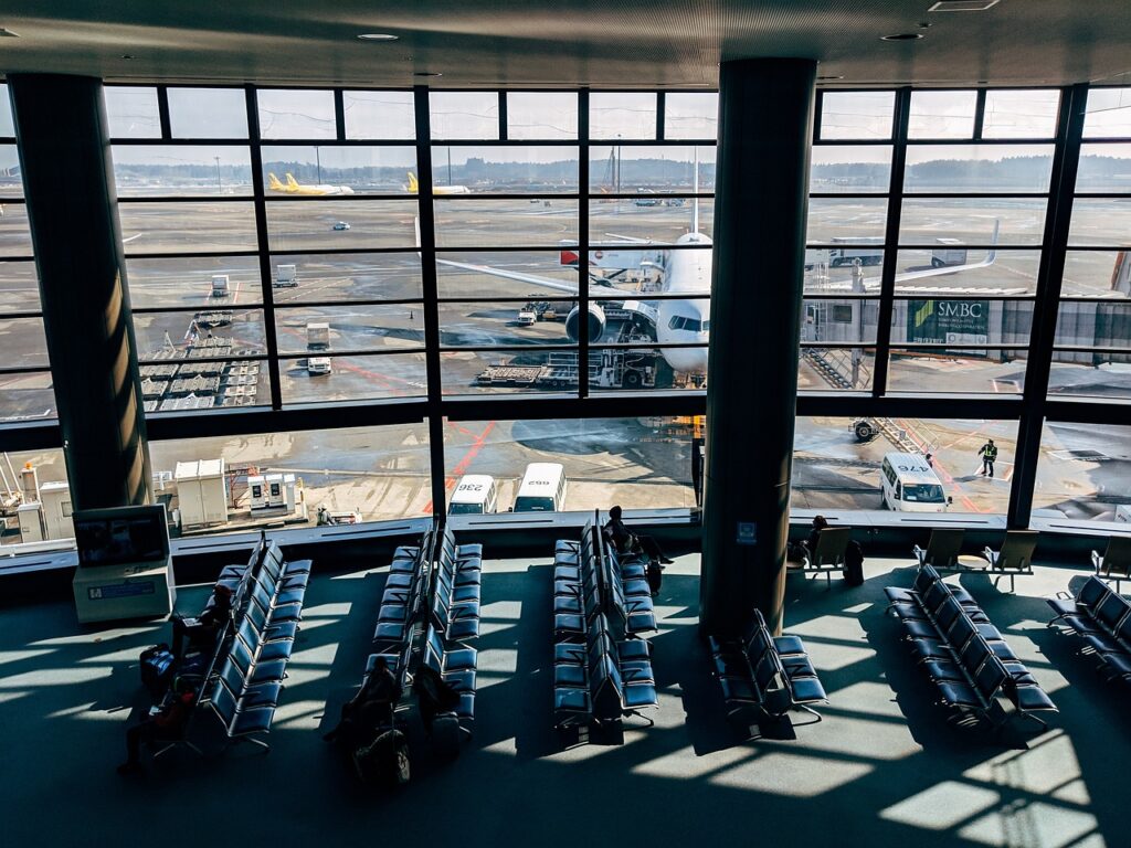 Passengers waiting in Bari airport terminal overlooking parked aircraft