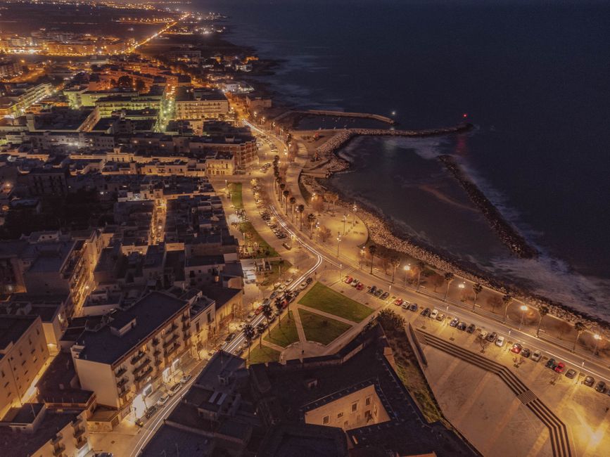 Veduta aerea notturna di Bari con lungomare illuminato e porto
