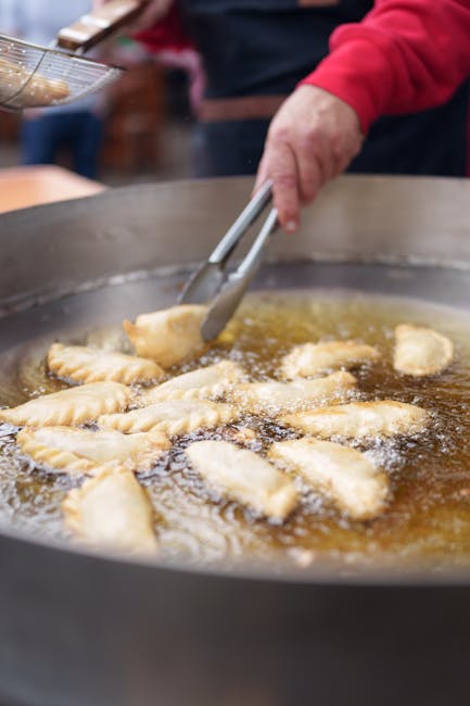 Panzerotti die in grote pan worden gefrituurd, tang zichtbaar op markt in Bari