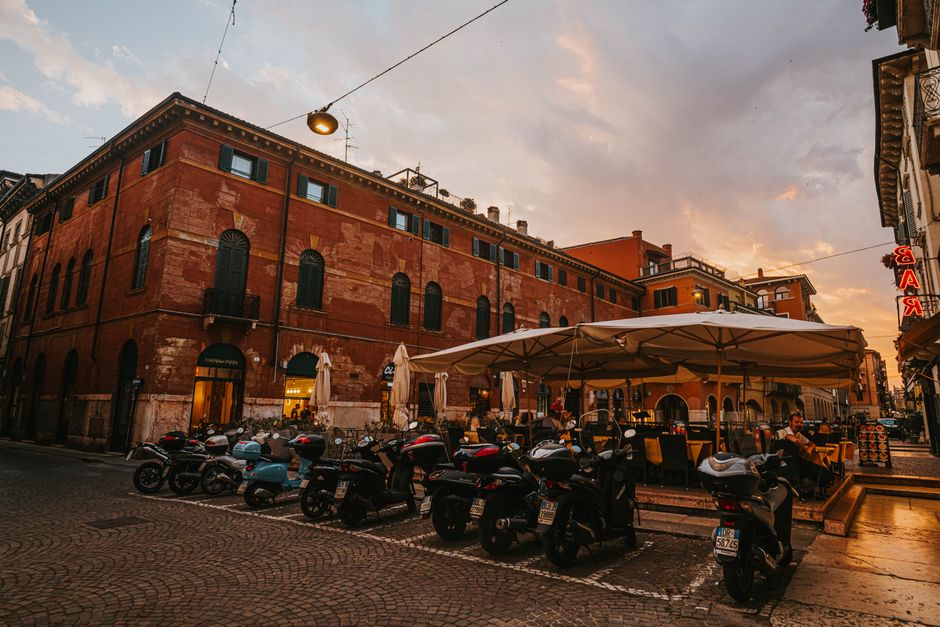 Rollerreihe vor einem Café vor historischen Gebäuden in Bari bei Sonnenuntergang