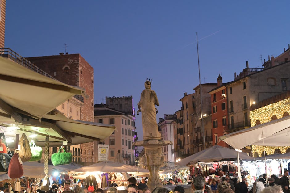 Mercato serale affollato a Bari con bancarelle e statua centrale