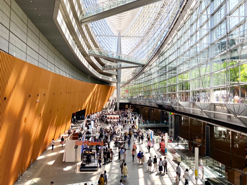Crowded modern glass atrium hosting a busy temporary exhibition in Bari