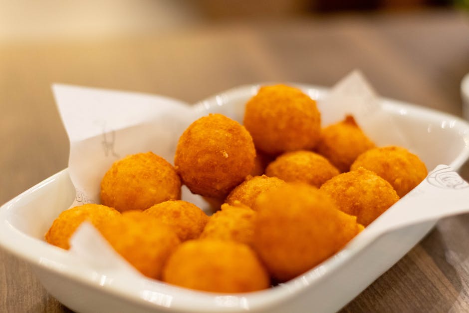 Golden arancini balls piled in a white dish, Catania snack.