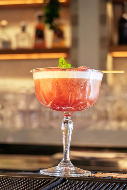 Cocktail rose en coupe, décor de menthe dans un bar de Catane