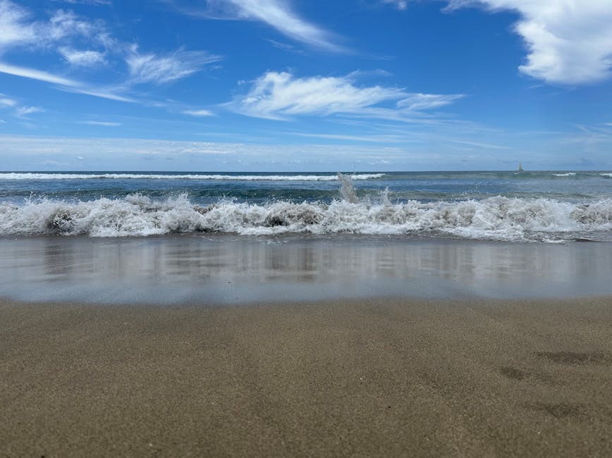 Onde che si infrangono su sabbia dorata, cielo azzurro sopra Catania