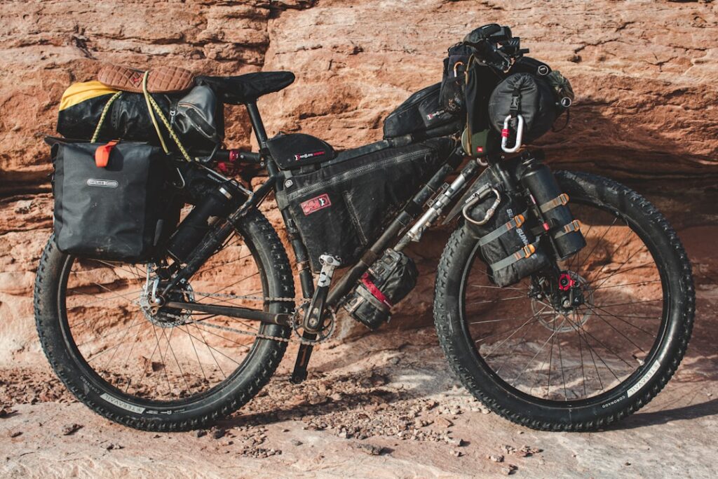 Vollbepacktes Bike mit Gepäcktaschen vor roter Felswand