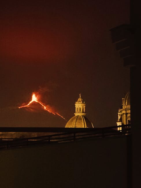 Etna in eruzione dietro la cupola barocca nella notte di Catania