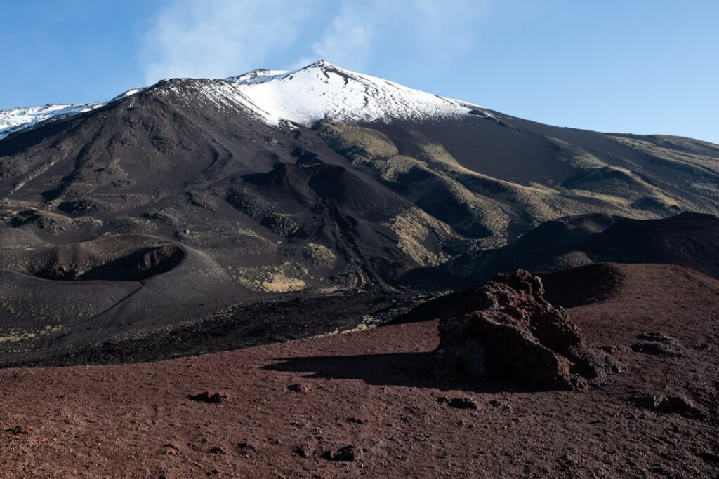 Blick auf schneebedeckten Ätna mit dunklen Lavaströmen bei Catania