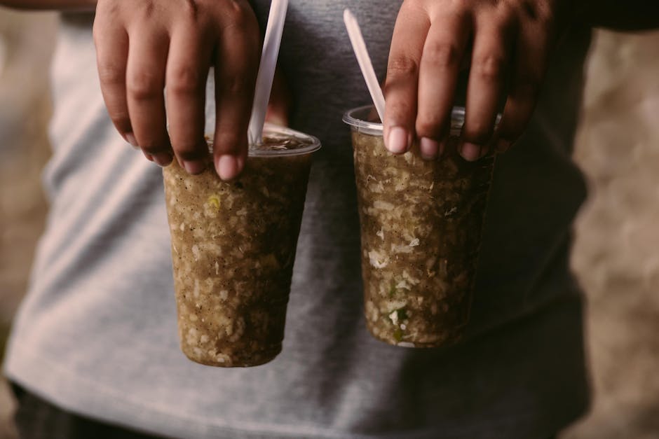 Hands holding two greenish granita cups, Catania street snack