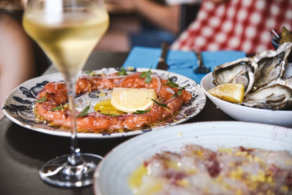Plate of salmon, oysters and glass of wine on Catania terrace