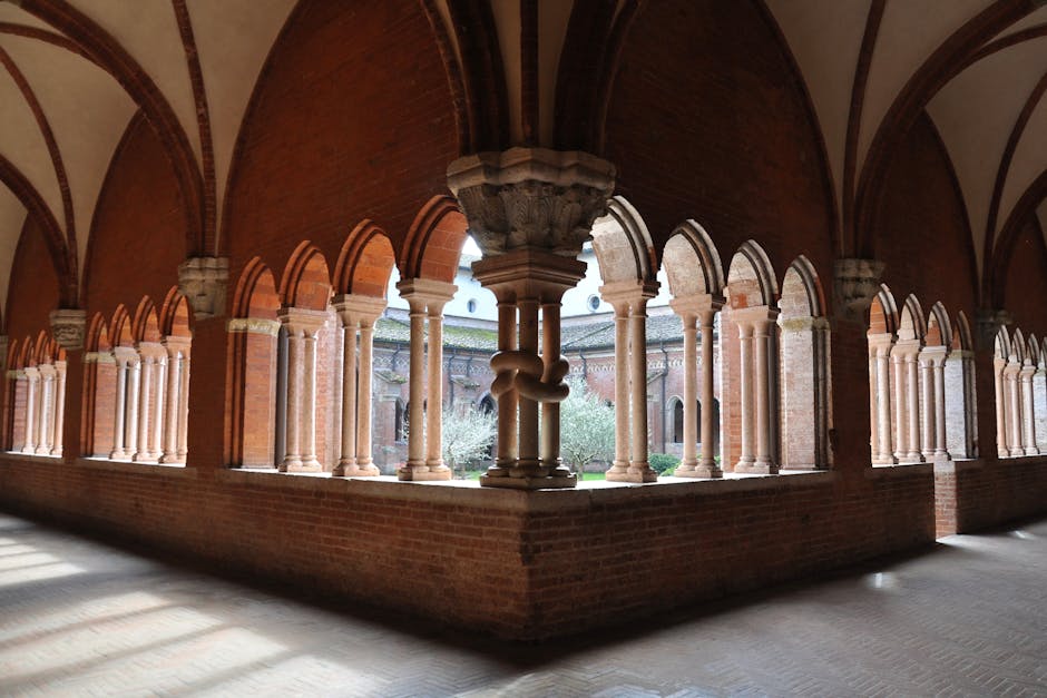Cloître à arcs en brique et colonnes donnant sur un jardin à Catane