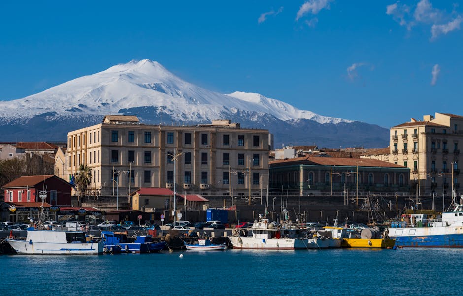 Fishing boats in Catania harbor with snow-capped Mount Etna looming