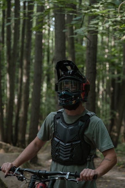 Biker mit Vollvisierhelm und Schutzweste im Wald, Fahrradlenker sichtbar