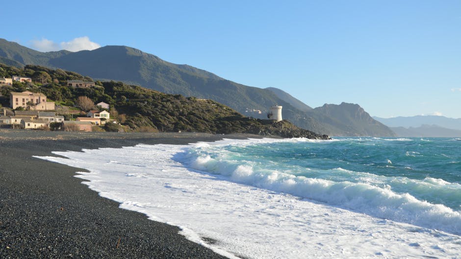 Plage de sable noir, vagues déferlantes et tour côtière en vue