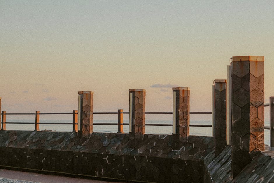 Hexagonal stone posts and metal railing along Catania seafront promenade at dusk