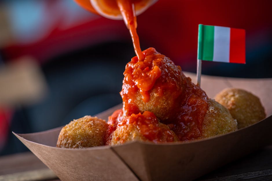 Arancini croustillants nappés de sauce tomate, petit drapeau italien à Catane