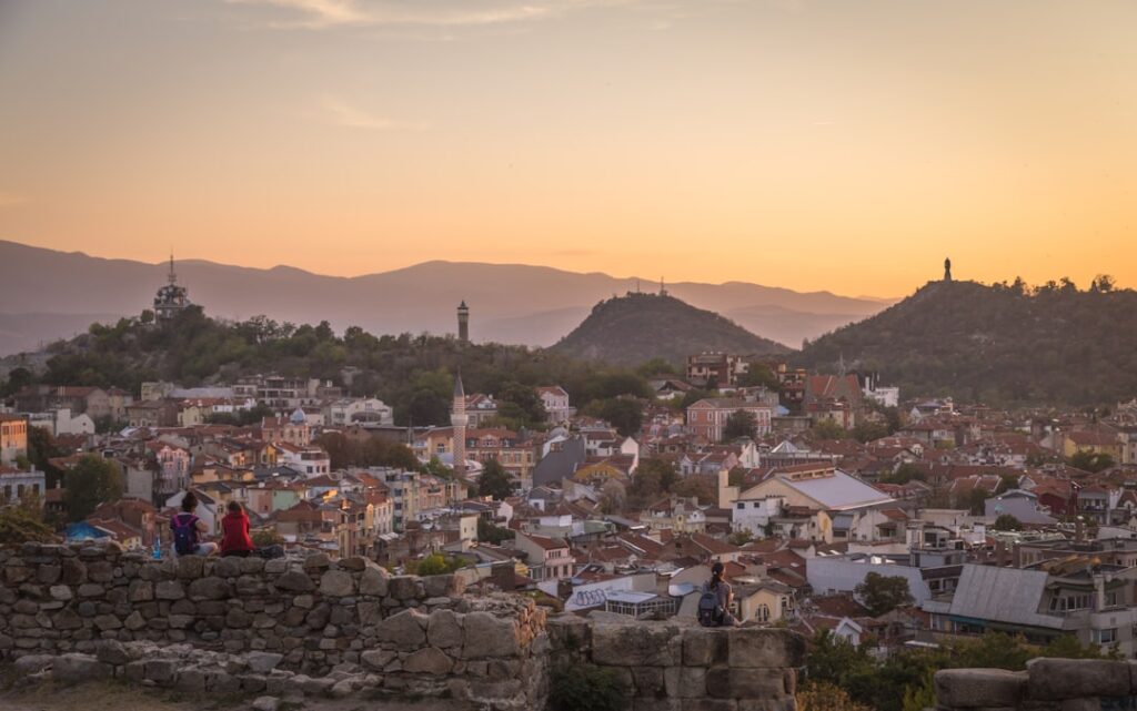 Panorama cittadino al tramonto con colline e spettatori sulle rovine
