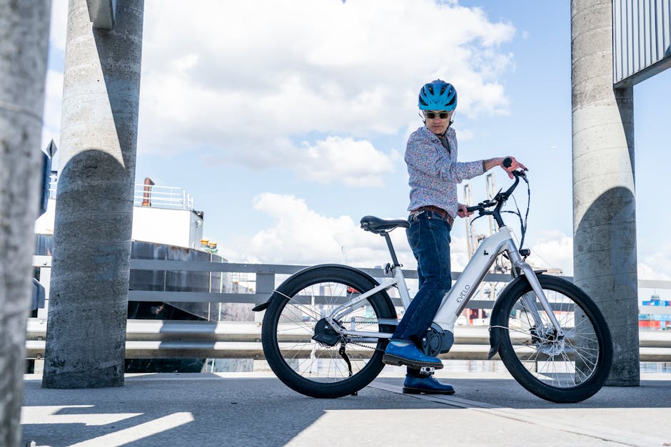 Person in blue helmet standing with white e-bike near industrial harbor