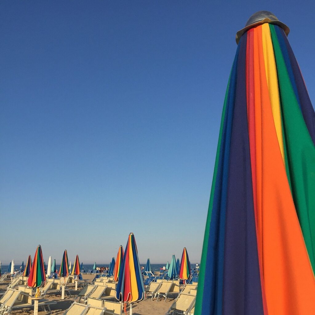 Kleurrijke parasols en ligstoelen op een strand bij Catane