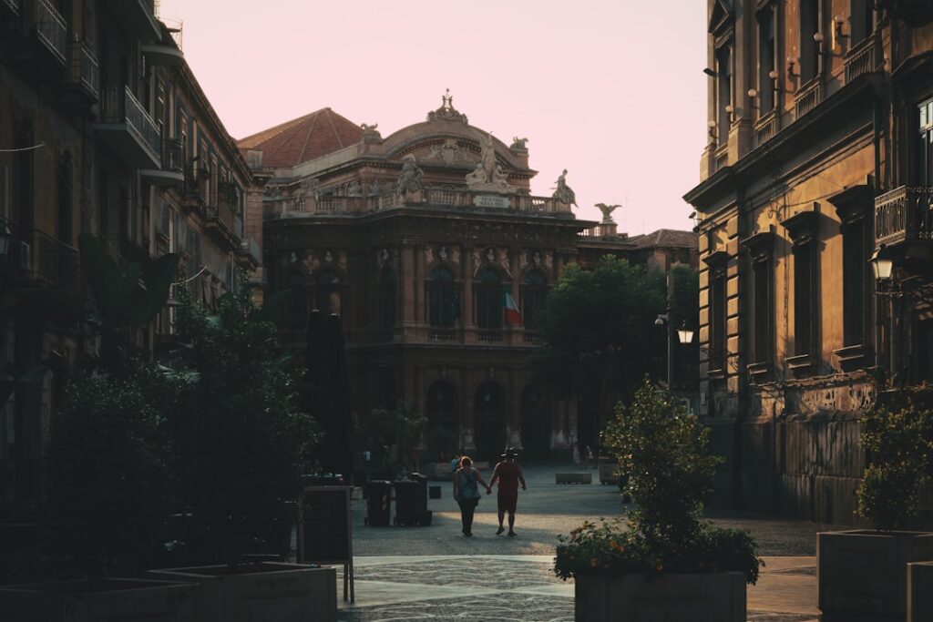 Para spacerująca ulicą w stronę Teatro Massimo w centrum Katanii