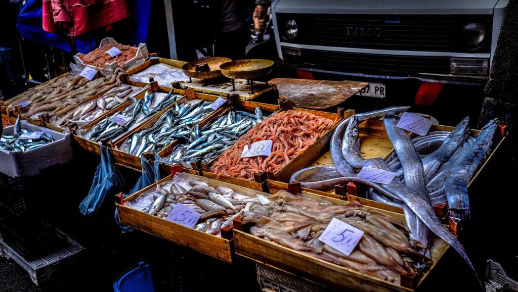 Fresh fish and shrimp displayed in wooden crates at Catania market