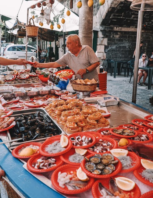 Vendor handing seafood plates to customer at bustling Catania street market