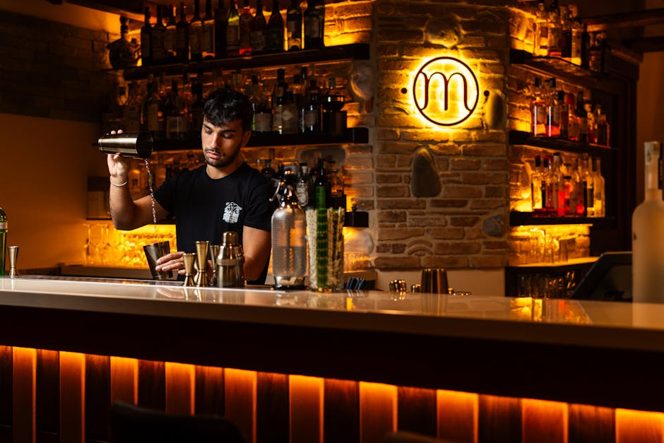 Barkeeper mischt Cocktails an einer warm beleuchteten Bar in Catania.