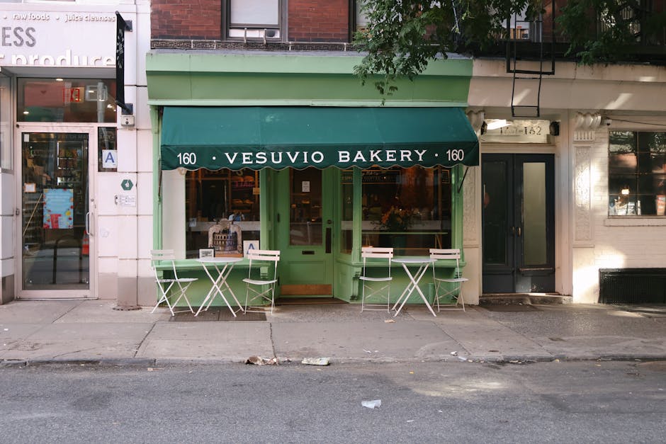 Bottega con tenda verde "Vesuvio Bakery" e tavolini in strada