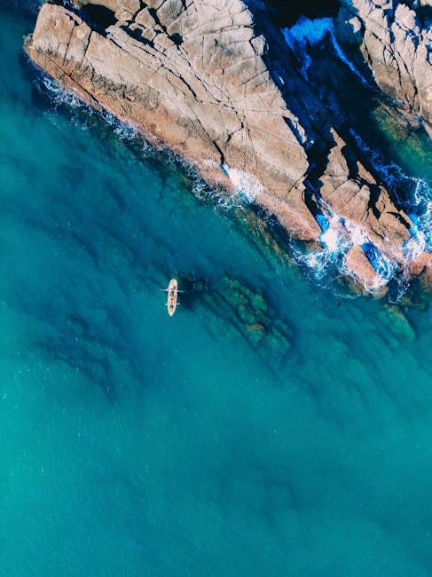 Aerial view of lone rowboat near rocky coastline off Catania