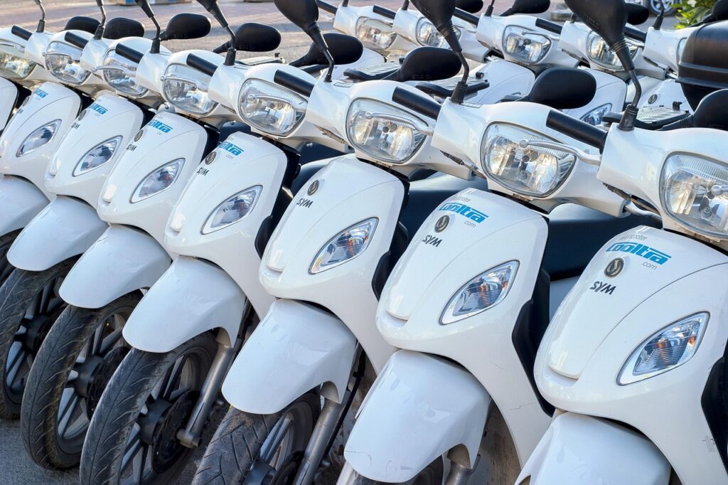 Row of white rental scooters lined up on a Catania street