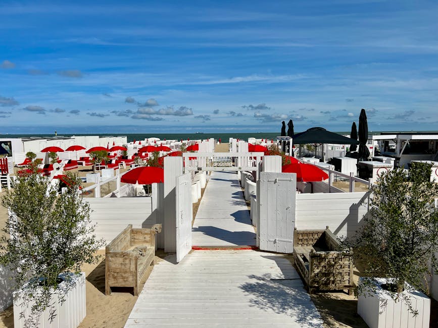 Wooden boardwalk leading into a Catania beach club with red umbrellas