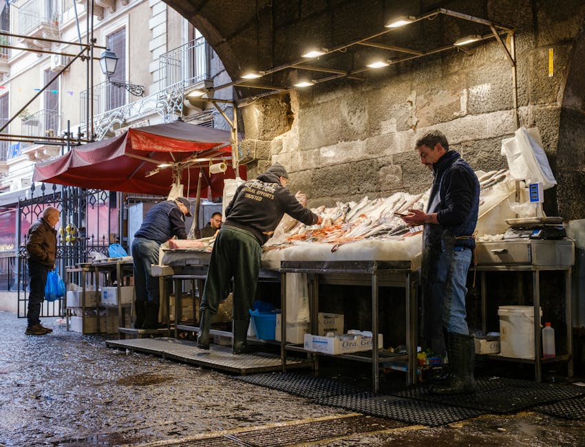 Étals de poisson humide sous arcade au marché de Catane, vendeurs occupés