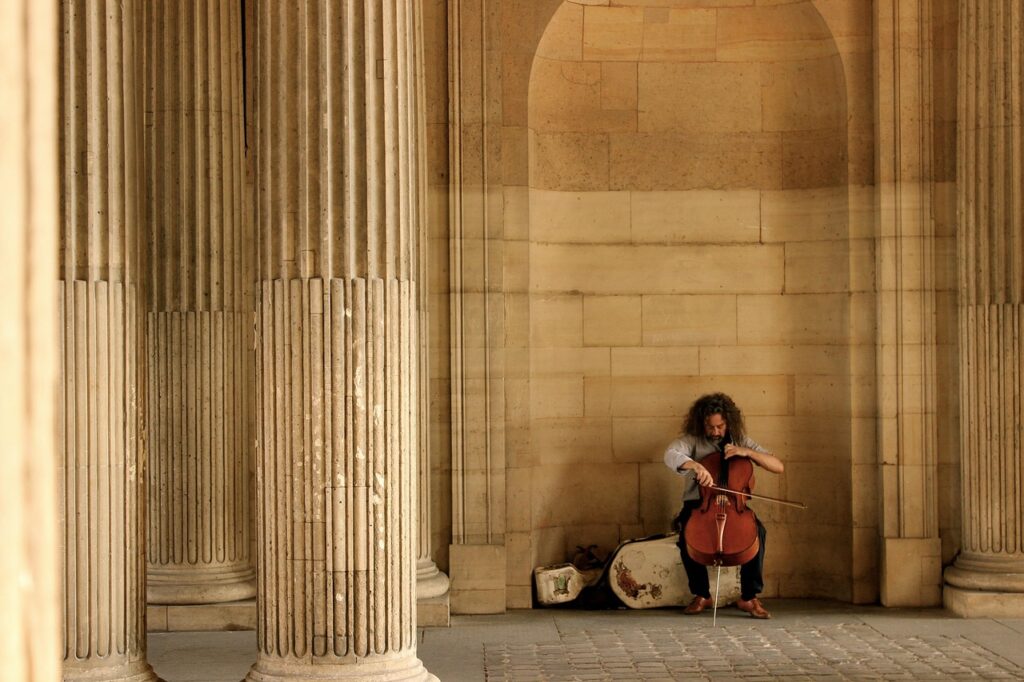 Cellist spielt in einer steinernen Arkade zwischen Säulen in Catania.