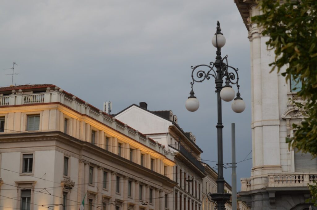 Straßenlaterne in Catania vor klassischen Gebäuden bei Gewitterhimmel