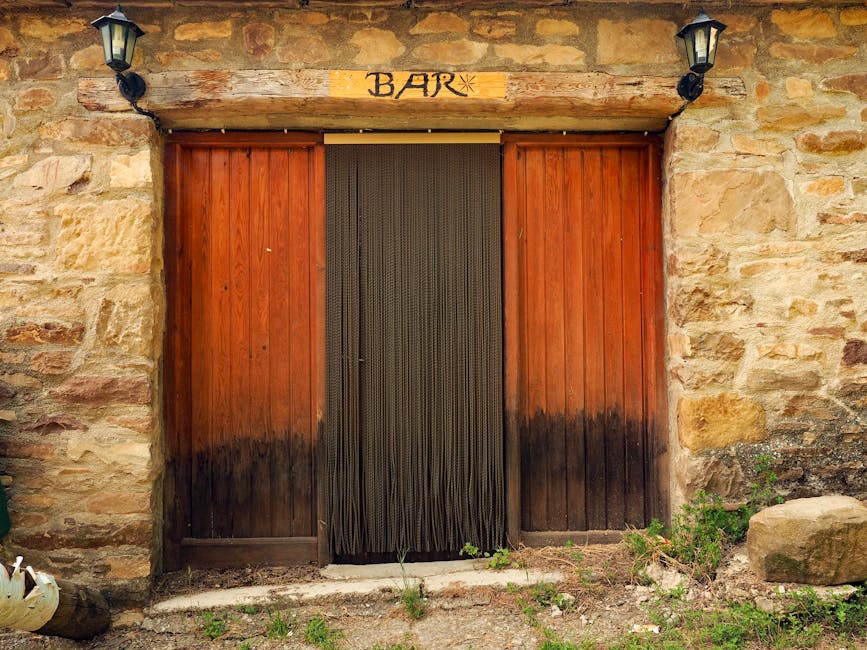 Rustic Catania bar entrance with wooden doors and a bead curtain.