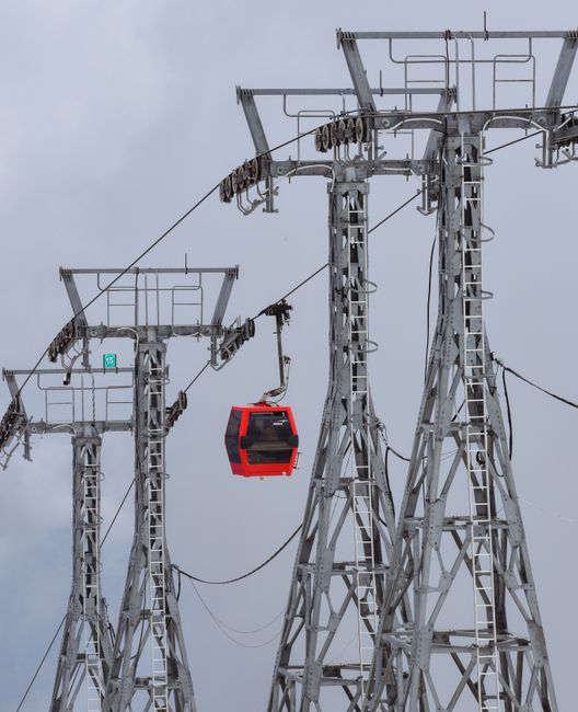 Cabine de téléphérique rouge entre pylônes métalliques menant vers l'Etna