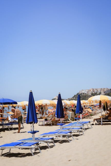 Piaszczysta plaża z niebieskimi leżakami i parasolami przy Catanii