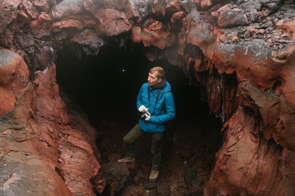 Explorateur avec appareil photo dans un tunnel de lave aux parois rouges près de Catane