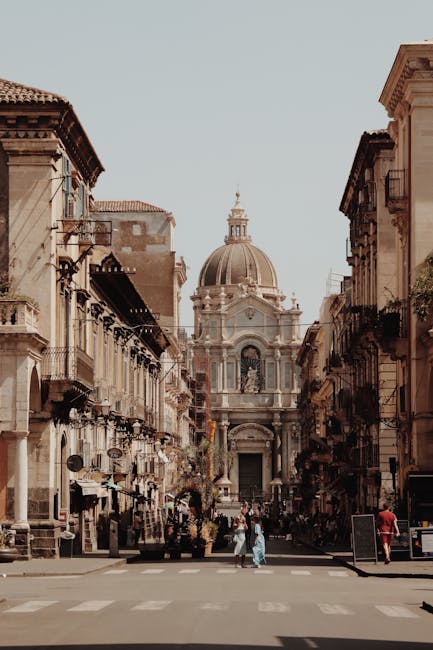 Straat in Catania met barokke kerk en koepel op de achtergrond