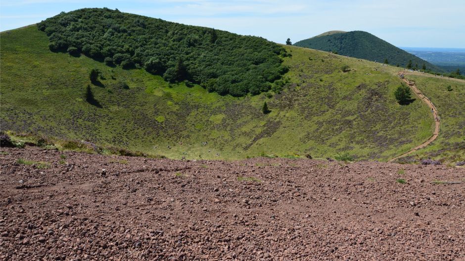 Cratère herbeux avec sentier de randonnée longeant les collines volcaniques