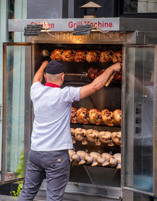 Sprzedawca przy piecu z pieczonymi kurczakami na rożnie w Katanii